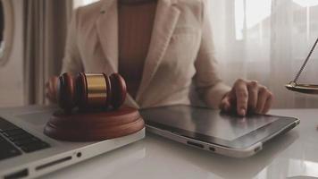 Justice and law concept.Male judge in a courtroom with the gavel, working with, computer and docking keyboard, eyeglasses, on table in morning light video