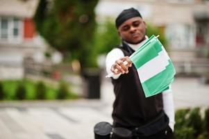 joven camarógrafo afroamericano profesional sosteniendo una cámara profesional con banderas nigerianas en las manos. foto
