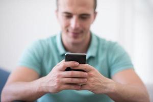 young man using a mobile phone  at home photo