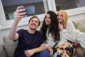 jóvenes felices, musulmanes tomando selfie en casa foto