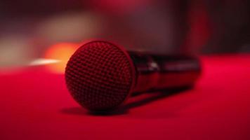 The microphone lies on the stage against the background of a concert show, performance or karaoke. Dynamic background color bokeh. The concept of a musical instrument video
