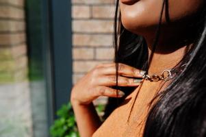 Close up hands of beauty young black woman, wear orange outfit, touch necklace. photo