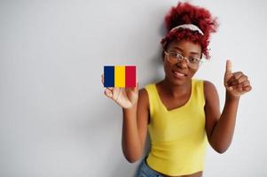 African woman with afro hair, wear yellow singlet and eyeglasses, hold Chad flag isolated on white background, show thumb up. photo