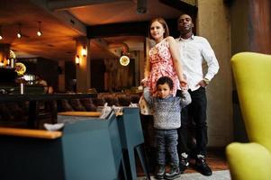 Happy multiethnic family with boy kid spend time at restaurant. Relationships of african man and white european woman. photo