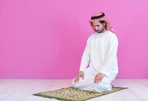 young arabian muslim man praying on the floor at home photo