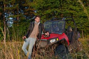man enjoying beautiful sunny day smoking a cigarette while taking a break from driving a off road buggy car photo