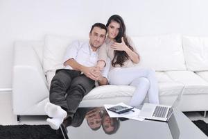 una pareja alegre se relaja y trabaja en una computadora portátil en una casa moderna foto