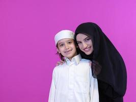 portrait of muslim mother and son on pink background photo