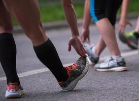 runners team warming up and stretching before morning training photo