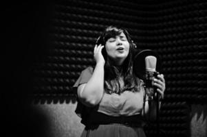 joven cantante asiático con micrófono grabando una canción en un estudio de grabación de música. foto