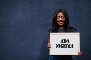 mujer africana sostiene una pizarra blanca con la inscripción aba nigeria. concepto de ciudad más poblada de África. foto