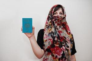 joven musulmana árabe vestida con hijab tiene pasaporte de la república de kazajstán sobre fondo de pared blanca, retrato de estudio. foto