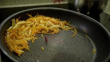 Sliced onion and carrot pieces fried on a pan close-up. Frying onions and carrot in sunflower oil in a hot pan video