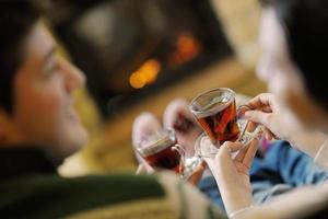 Young romantic couple sitting on sofa in front of fireplace at home photo