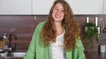 Young woman with long red curly hair laughs and looks at the camera while talking and laughing video