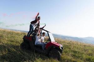 excited people having fun enjoying beautiful sunny day holding colorful torches while driving a off road buggy car photo