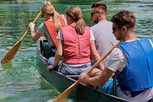 Group adventurous explorer friends are canoeing in a wild river photo