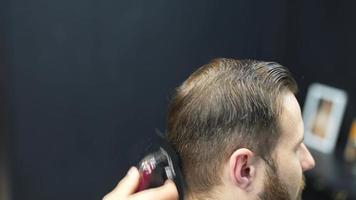 Barber trims hair of male client with comb and clippers