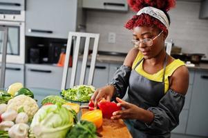 African american woman preparing healthy food at home kitchen. She cuts red pepper. photo