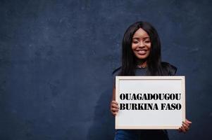 African woman hold white board with Ouagadougou Burkina Faso inscription. Most populous city in Africa concept. photo