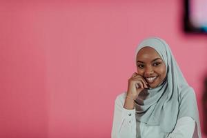 Portrait of young modern muslim afro beauty wearing traditional islamic clothes on plastic pink background. Selective focus photo