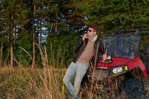 man enjoying beautiful sunny day smoking a cigarette while taking a break from driving a off road buggy car photo