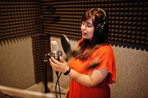 Young asian singer with microphone recording song in record music studio. photo