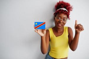 African woman with afro hair, wear yellow singlet and eyeglasses, hold Democratic Republic of the Congo flag isolated on white background, show thumb up. photo