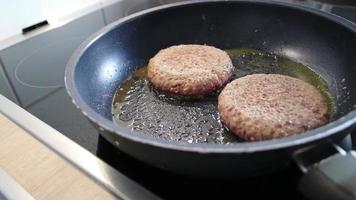 Frozen burger patties burger meat sizzling in hot pan with fat and oil as delicious selfmade hamburger bbq meatballs as unhealthy fast food lunch with lots of calories and cholesterol in frying pan video