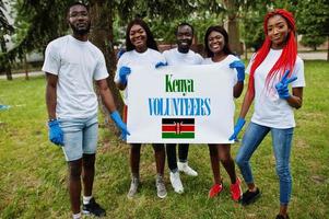 grupo de felices voluntarios africanos se mantienen en blanco con la bandera de kenia en el parque. Concepto de voluntariado, caridad, personas y ecología de los países africanos. foto