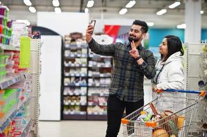 Asian couple wear shopping together in supermarket, making selfie by phone. photo
