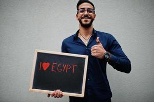 I love Egypt. Middle eastern man wear blue shirt, eyeglasses, hold board. photo
