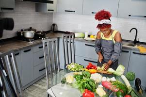 African american woman filming her blog broadcast about healthy food at home kitchen. She cuts the cabbage. photo