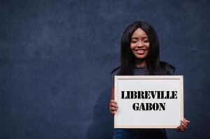 African woman hold white board with Libreville Gabon inscription. Most populous city in Africa concept. photo