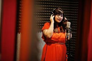 Young asian singer with microphone recording song in record music studio. photo