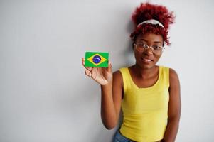 African american woman with afro hair, wear yellow singlet and eyeglasses, hold Brazil flag isolated on white background. photo