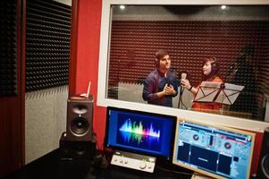 Young asian duet singers with microphone recording song in record music studio. photo