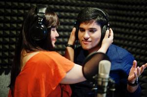 Young asian duet singers with microphone recording song in record music studio. photo