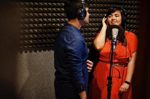 Young asian duet singers with microphone recording song in record music studio. photo