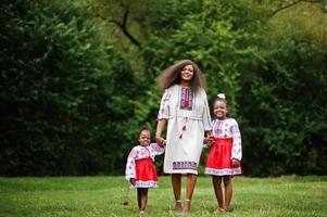 madre africana con hijas vestidas con ropa tradicional en el parque. foto