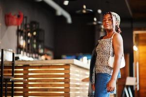 Lovely african american woman with dreadlocks in leopard outfit at cafe. Beautiful cool fashionable black young girl indoor. photo