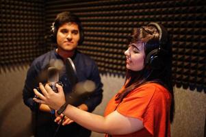 Young asian duet singers with microphone recording song in record music studio. photo