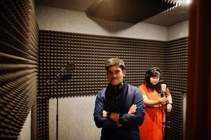 Young asian duet singers with microphone recording song in record music studio. photo