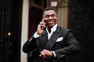 retrato de joven y apuesto hombre de negocios afroamericano en traje habla por teléfono móvil, prepárate para la reunión. foto