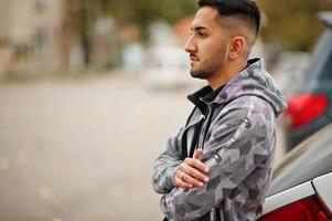 Student kuwaiti man wear at hoodie stand near car. photo