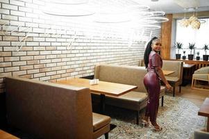 Beautiful african american woman in red leather costume pose at restaurant. photo