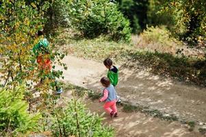 Back of three kids walking on wood mountains. Family travel and hiking with childrens. photo