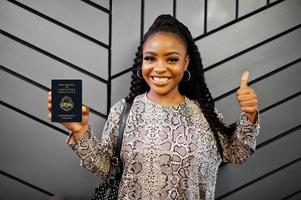 Close up portrait of young positive african american woman holding Costa Rica passport and thumbs up. photo