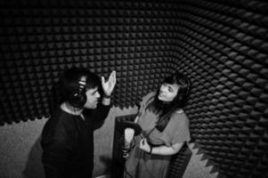 jóvenes cantantes de dúo asiáticos con micrófono grabando una canción en un estudio de grabación de música. foto