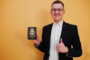 Young handsome man holding Commonwealth of The Bahamas passport id over yellow background, happy and show thumb up. Travel to America countries. photo